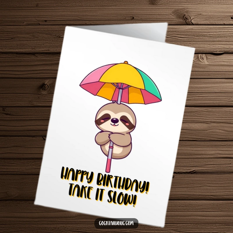 Funny Free Printable Sloth Birthday Card: A smiling sloth hangs from a cocktail umbrella, wishing a lazy birthday.